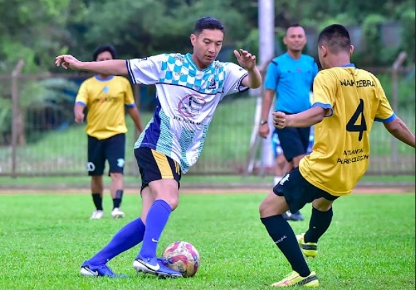 Kapolres Cilegon AKBP Kemas Indra Natanegara menggiring bola dibayangi pemain dari tim wartawan.